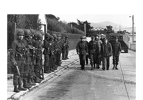 El contraalmirante Carlos Büsser recorre Ross Road. Los ingleses acaban de rendirse y él se dirige hacia donde está Rex Hunt, a quien le dice: “Hemos recuperado lo que nos pertenece por derecho y vamos a permanecer aquí para siempre”